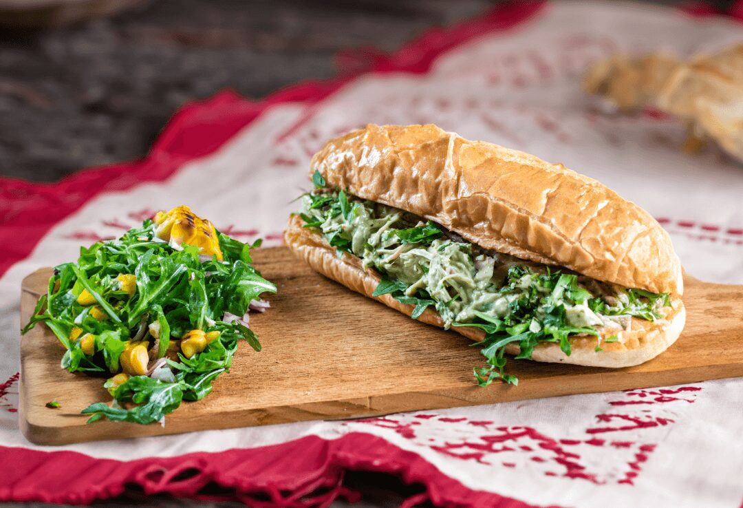 a sandwich on a cutting board next to a salad