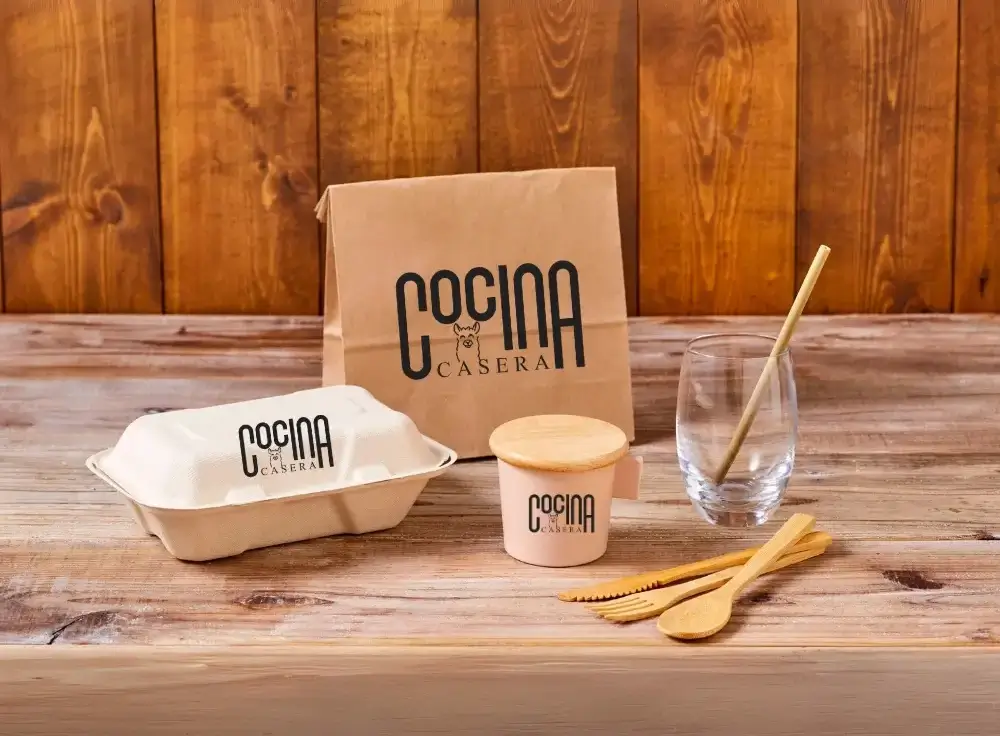 A wooden table displaying a paper box alongside utensils, creating a simple dining setup.